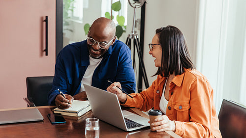 Co-workers brainstorming and laughing during a casual discussion in a modern office