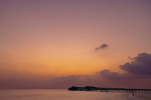 Serene evening sunset over an island with a calm sea and a beautiful pier