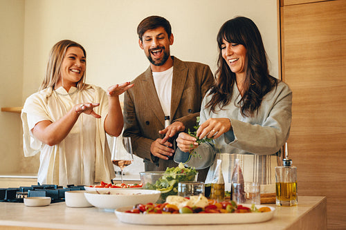Friends bonding and preparing food together during a home dinner gathering
