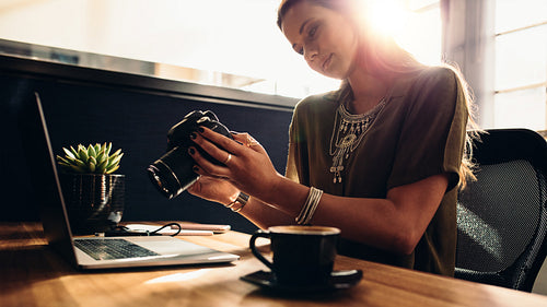 Young female photographer watching her camera while editing her vlog on computer.