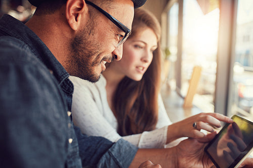 Couple using digital tablet at cafe