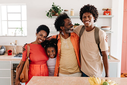 Family of four standing together after their morning routine at home, ready to start their day