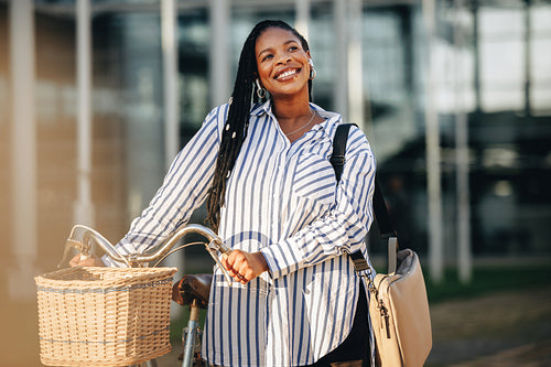 Cheerful young business woman commuting to work with a bicycle