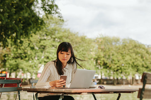 Chinese woman using smart phone in a outdoor cafe