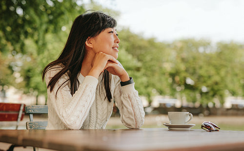 Asian woman spending free time at outdoor cafe