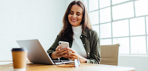 Happy business woman reading a message on her smartphone