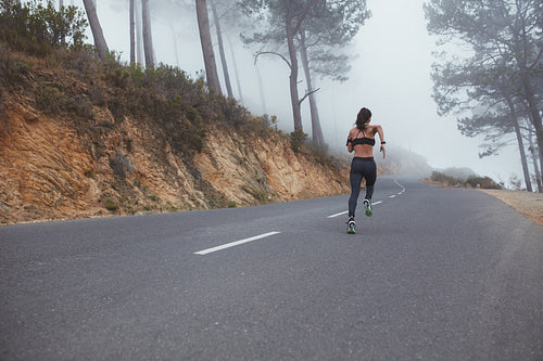 Female runner athlete sprinting on country road