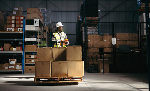 Warehouse employee holding a loaded pallet jack in a logistics centre