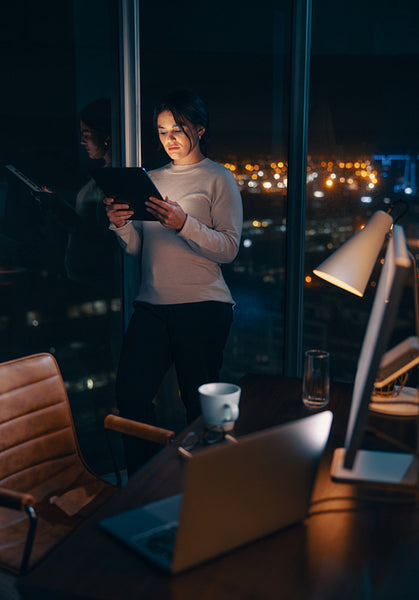Business woman working late in her office, using a tablet to analyse data