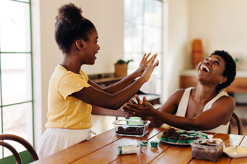 Fun brigadeiro making: Mother and daughter laughing happily while preparing chocolate truffles for a birthday