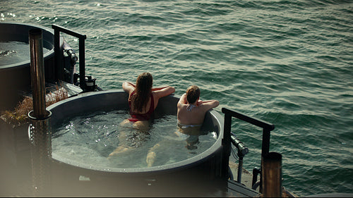 Women relaxing in outdoor hot tub during spa vacation retreat on open water