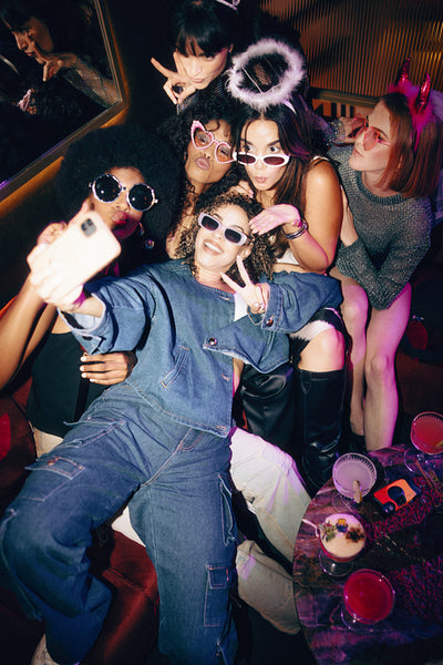 Group of friends taking a selfie during a lively party in colorful outfits