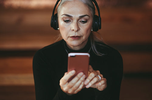 Senior businesswoman listening music from smart phone