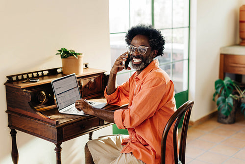 Happy african man working from home, engaging in a cheerful phone call
