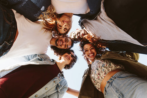 Smiling young friends forming a huddle
