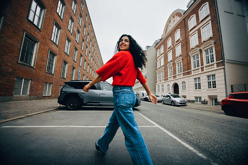 Walking through the city, the woman heads for an electric car charger while using her phone