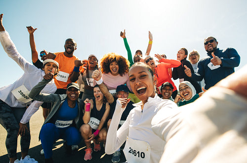 Diverse team celebrating success at marathon event outdoors with a selfie