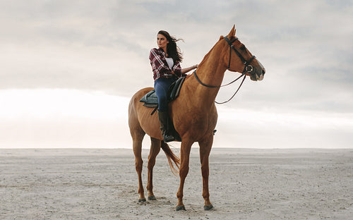 Woman on her horse at the beach