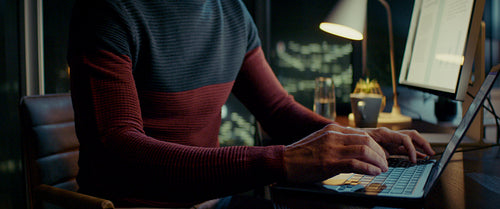 Businessman working late at night in office with city view