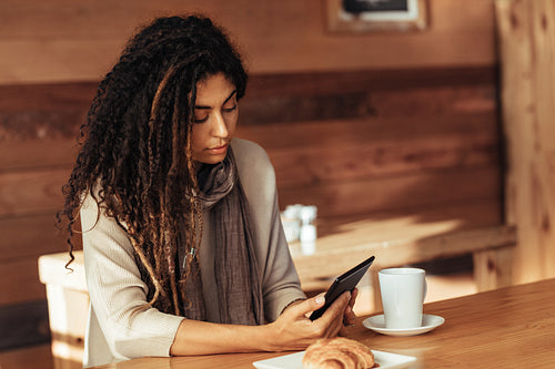 Woman sitting in a cafe looking at her mobile phone