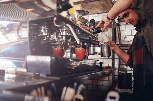 Barista using coffee maker to make a cup of coffee