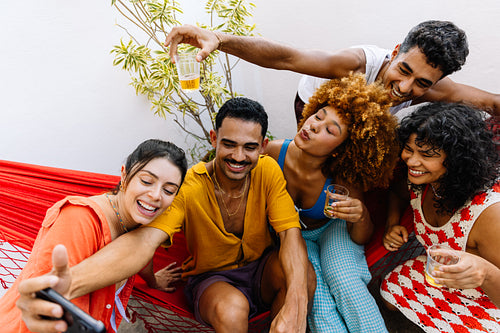 Group of friends enjoying a selfie while relaxing on a patio hammock