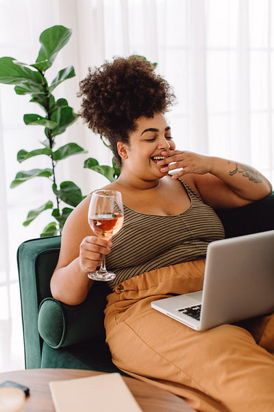 Woman with wine video chatting on laptop