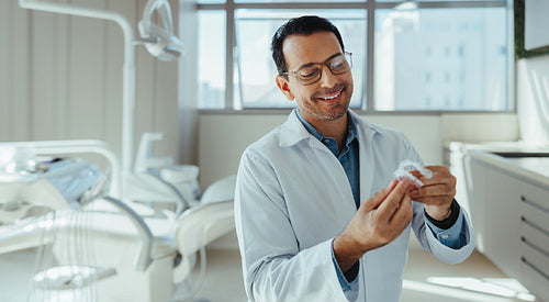 Male dentist examining dental aligners in modern clinic