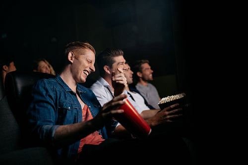 Young man with friends watching comedy movie