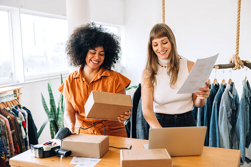 Happy clothing store owners preparing parcels for shipping