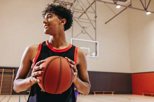 Young player holding a basketball indoors