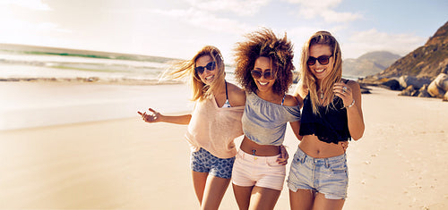 Group of female friends enjoy taking a walk together on the beach