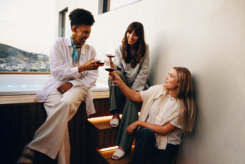 Three women enjoying an evening with wine on a patio
