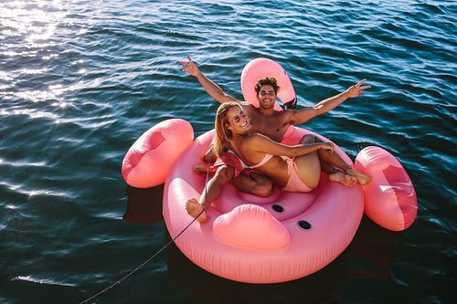Couple enjoying inflatable toy ride behind a boat