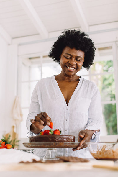 African woman decorating cake with strawberries