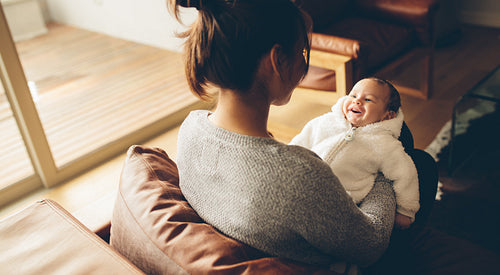 Cute little baby boy smiling in his mother's hands