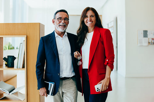 Two senior executives standing together and smiling in an office environment