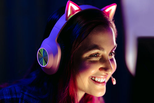 Enjoying esports, woman smiles at her computer screen with a headset on