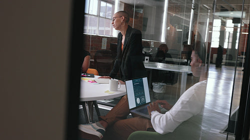 Young female leader addressing her team in an office meeting, giving a briefing on a project