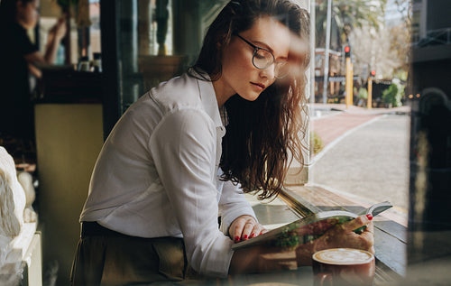 Woman reading book at coffee shop