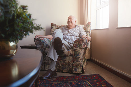 Elderly man sitting on arm chair at old age home