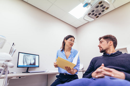 Dentist discussing report with patient at dental clinic