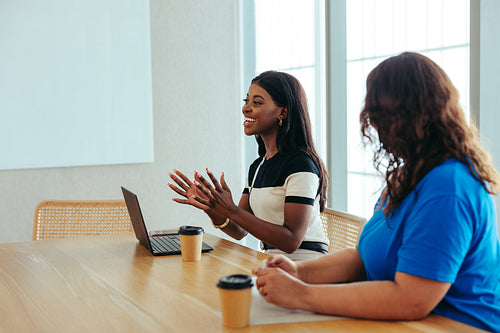 African businesswoman speaking confidently during a meeting while using a laptop
