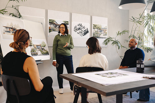 Diverse team engaged in a project management meeting with architectural designs