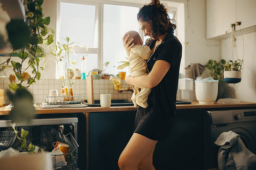 Mother holds baby in cozy kitchen at home