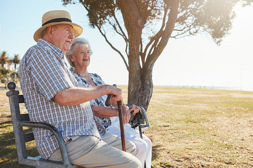 Senior man and woman sitting on a park bench outdoors