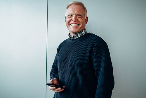 Senior businessman standing with mobile phone