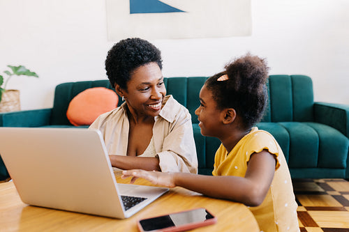 Happy mother and daughter browsing a kids' programme to watch on a laptop