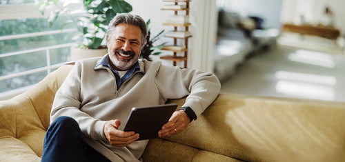 Senior man explores digital services on a tablet at home