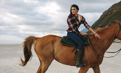 Girl riding a horse on coastline